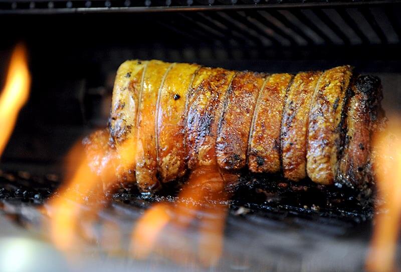 Wood-fired porchetta roasting on the grill