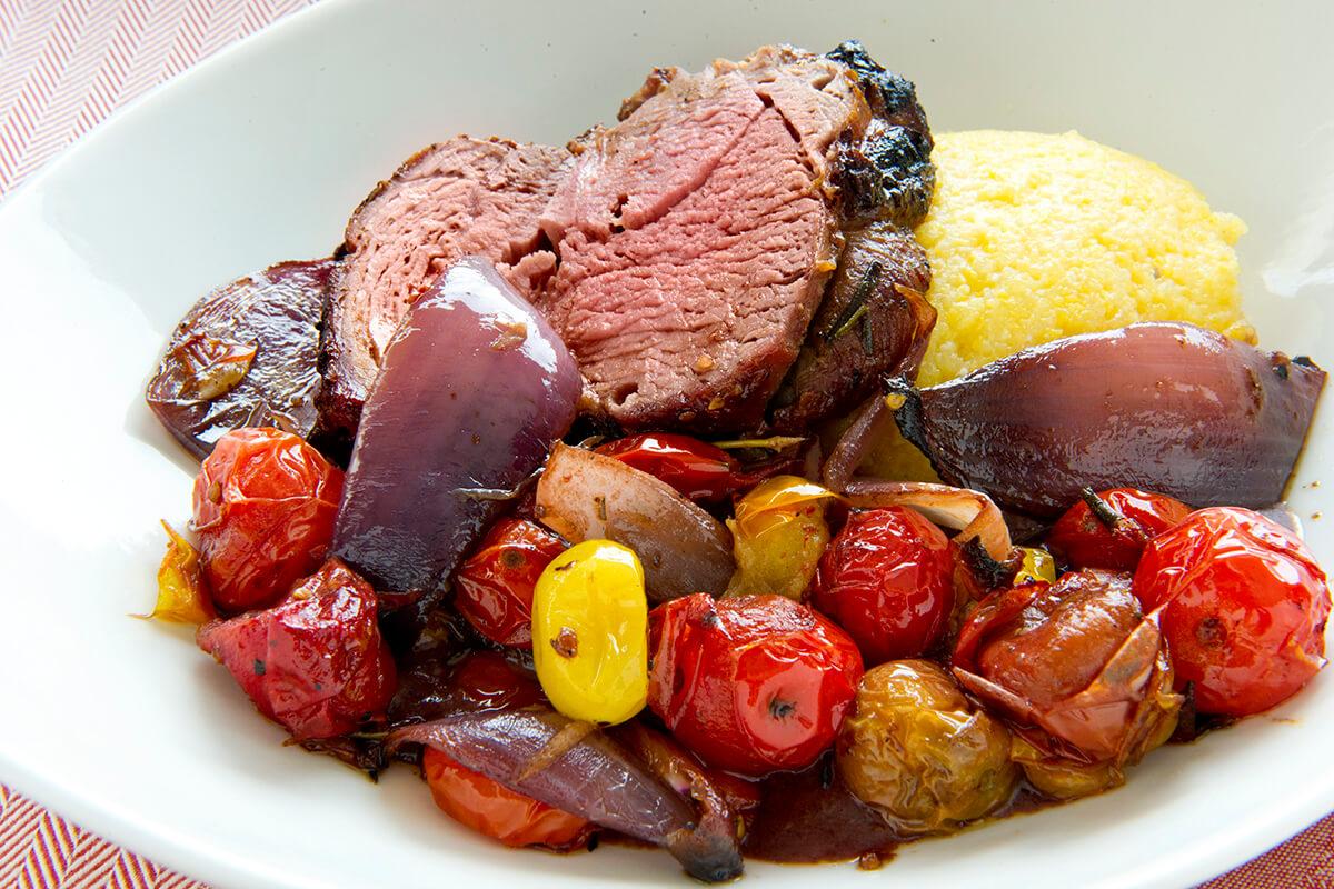 Image of Spit-roasted Leg of Lamb over Grits and Tomatoes